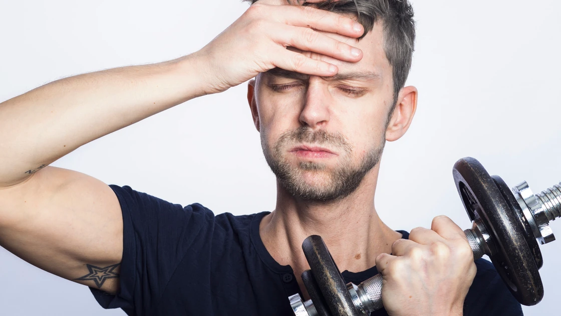 A man holding a dumbbell looking confused