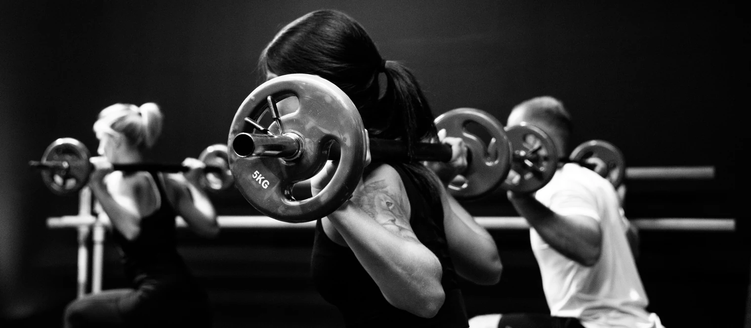 A group of people performing a split squat with a barbell.