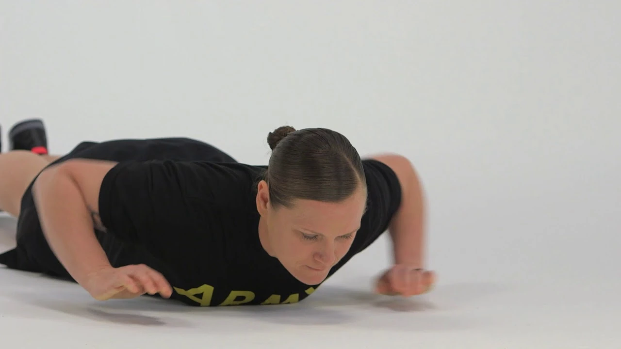 A woman lying down in the prone position performing a prone row.