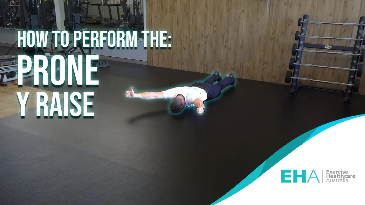 Person performing a prone Y raise while lying face down on the floor, lifting both arms overhead in a Y shape to strengthen the lower trapezius and shoulder stabilizing muscles.