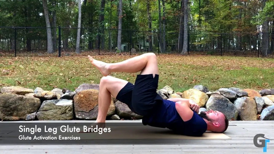 Person performing a single-leg glute bridge while lying on their back, lifting their hips off the ground with one foot planted and the opposite leg raised, targeting the glutes and hamstrings.