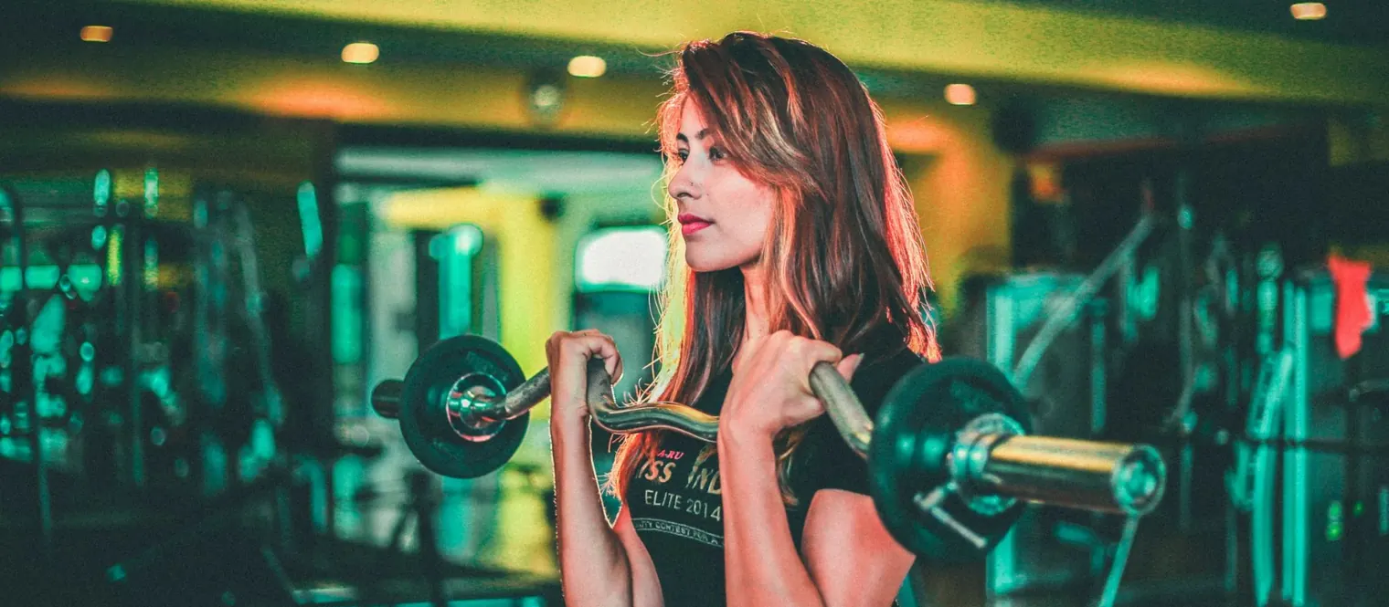 A woman doing bicep curls with an EZ bar