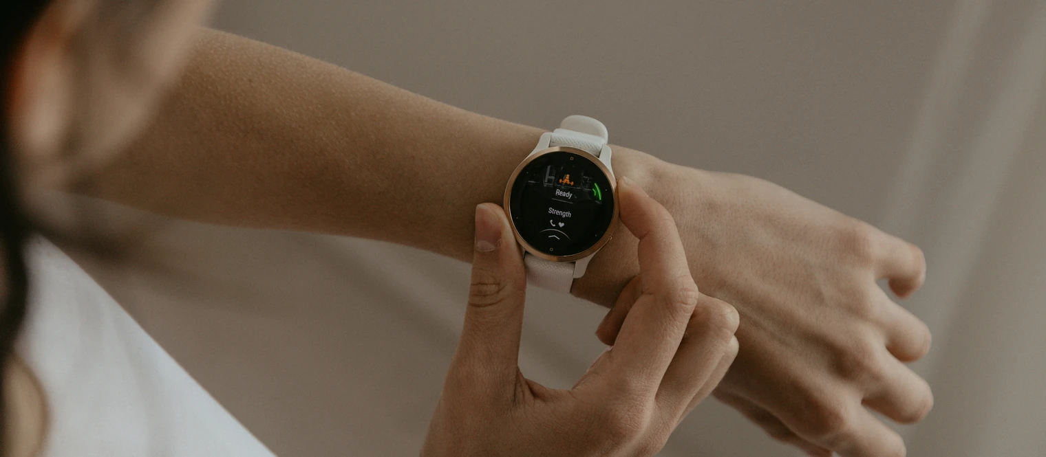 A woman loading a strength training app on a Garmin smartwatch