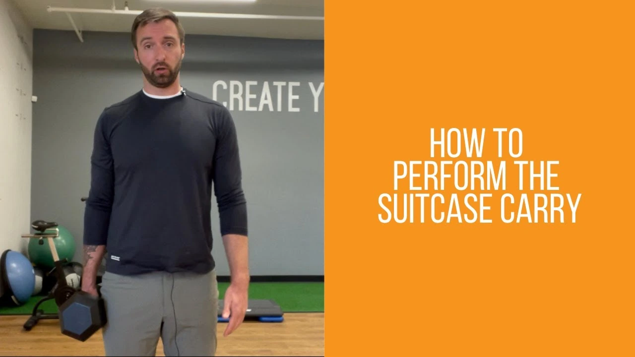 Person demonstrating a suitcase carry, standing upright with a dumbbell held at one side, keeping their shoulders level and torso straight to strengthen the core and grip.