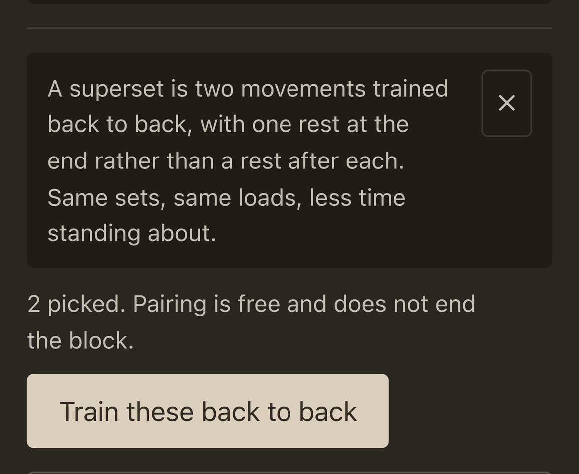 The day editor with two lifts picked. A line reads: a superset is two movements trained back to back, with one rest at the end rather than a rest after each. Same sets, same loads, less time standing about. Under it: 2 picked. Pairing is free and does not end the block. Then a button reading Train these back to back.