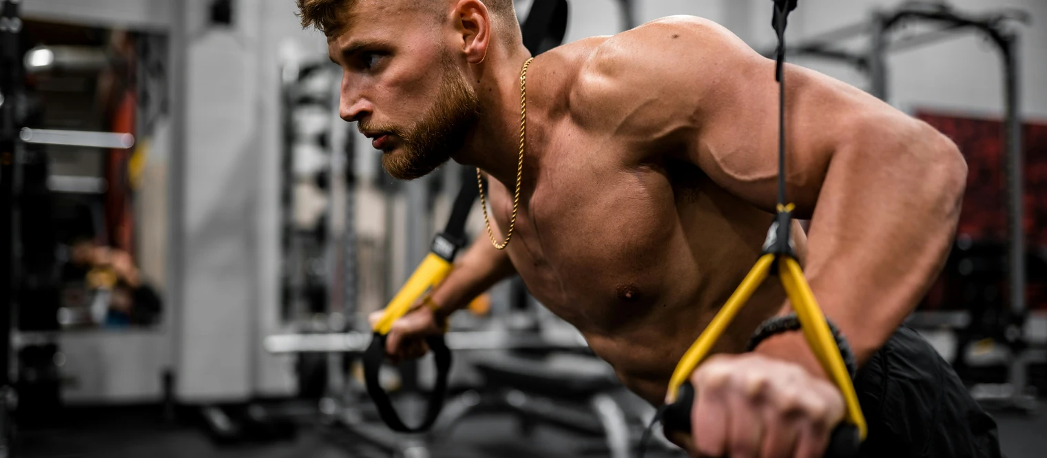 Man performing a suspended chest press using gym straps