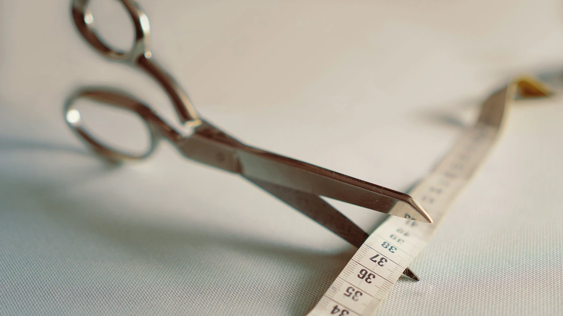 Scissors cutting through a measuring tape