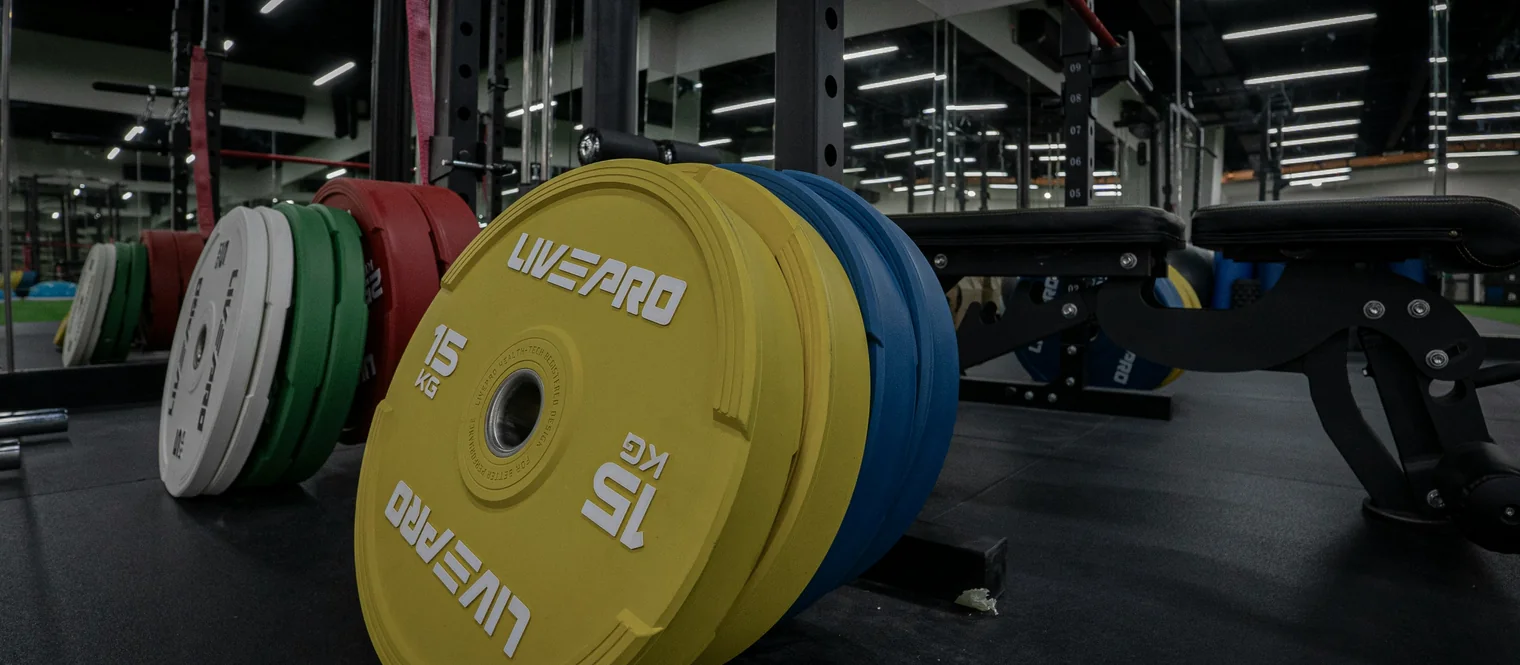 A stack of weight plates in the gym next to a weight bench.
