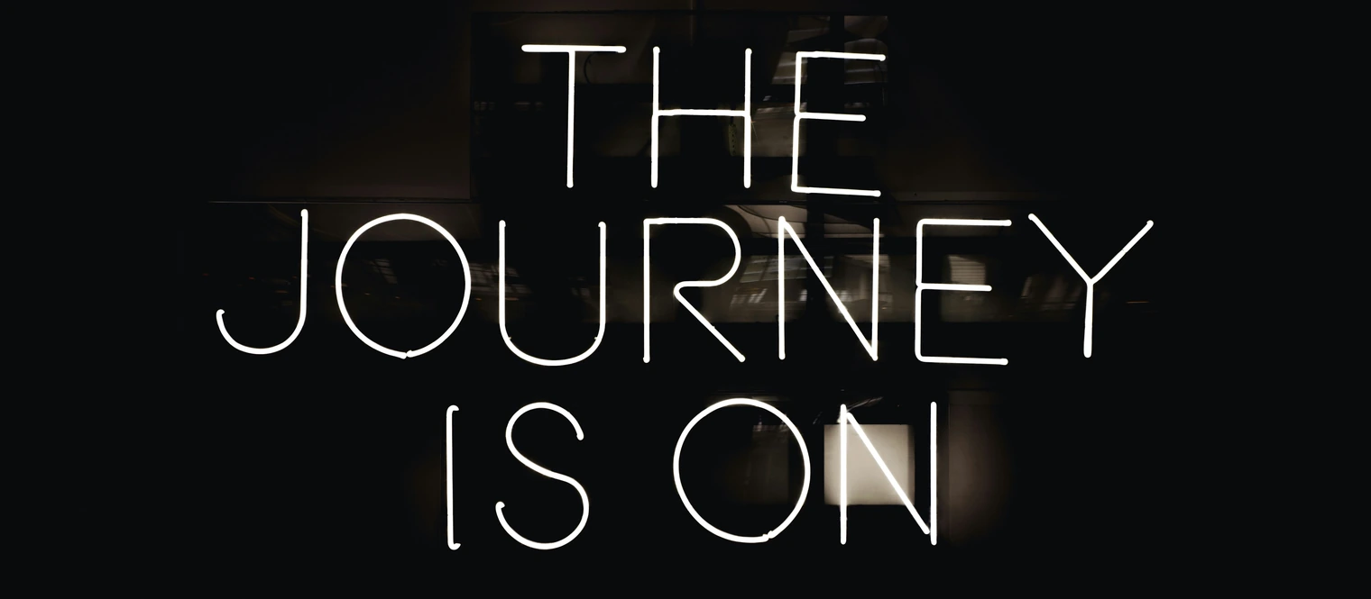 A neon sign that reads, The Journey is on. 